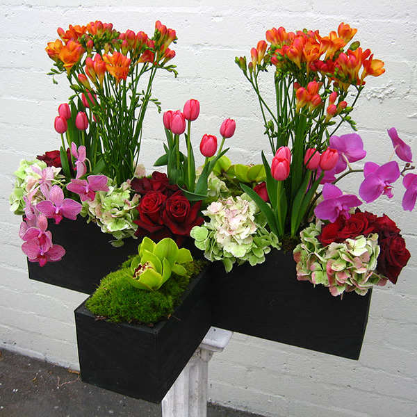Colorful floral arrangement in black rectangular containers with orchids, roses, tulips, and hydrangeas