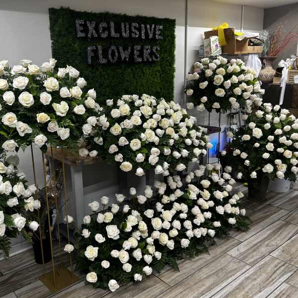 Large white rose arrangements displayed indoors around a green wall sign