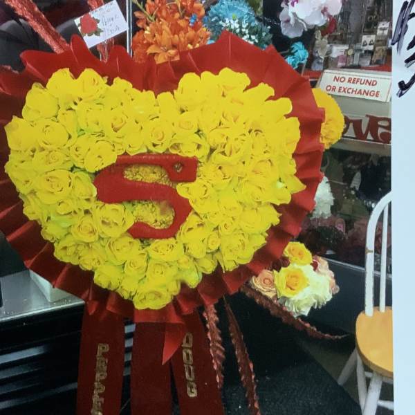 Heart-shaped yellow rose wreath with a red ribbon center and bow