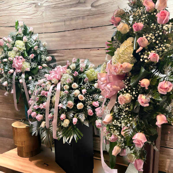 Three pink and white floral standing sprays with ribbons
