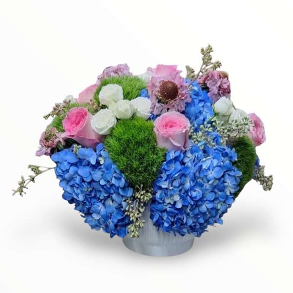 Blue hydrangeas and pink roses arranged in a white vase