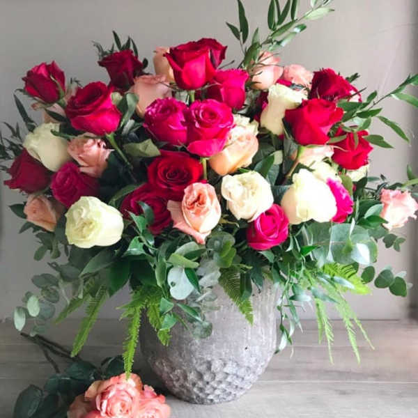 Large bouquet of red, pink, and cream roses in a silver vase
