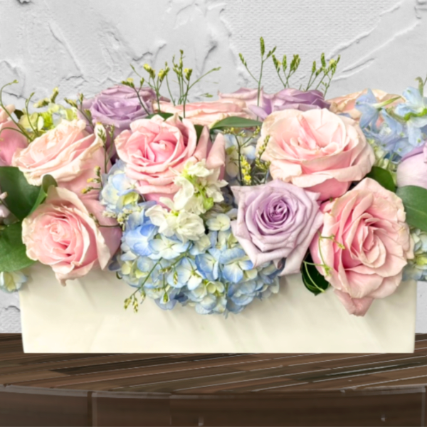 Pastel roses and hydrangeas arranged in a white box