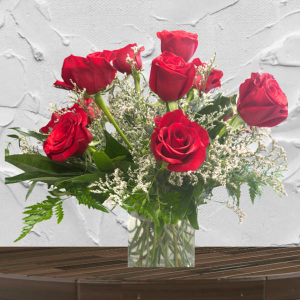 Red roses arranged in a clear glass vase with white filler flowers