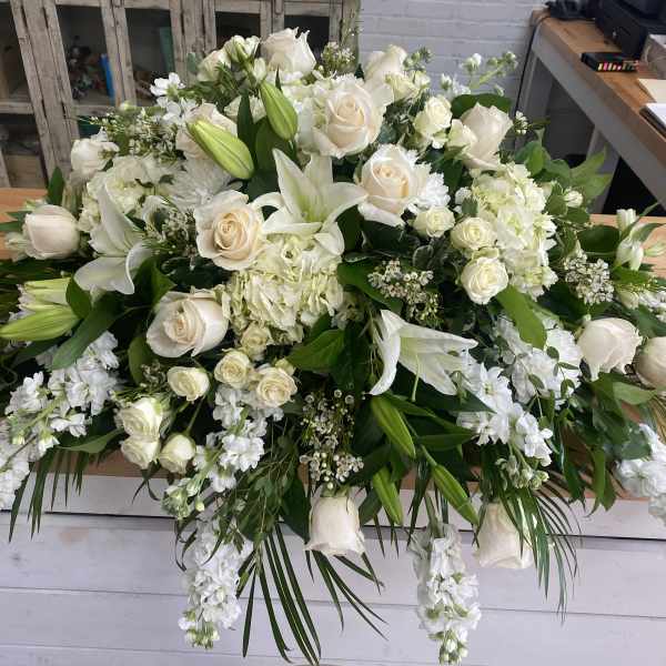 Large white floral arrangement with roses and lilies on a table