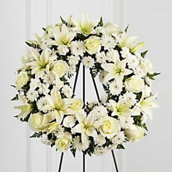 White floral wreath on a black easel stand