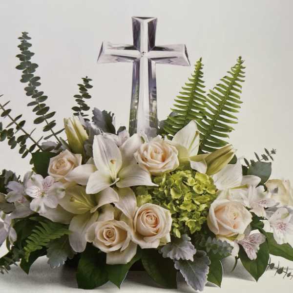 White floral arrangement with roses and lilies beneath a clear cross