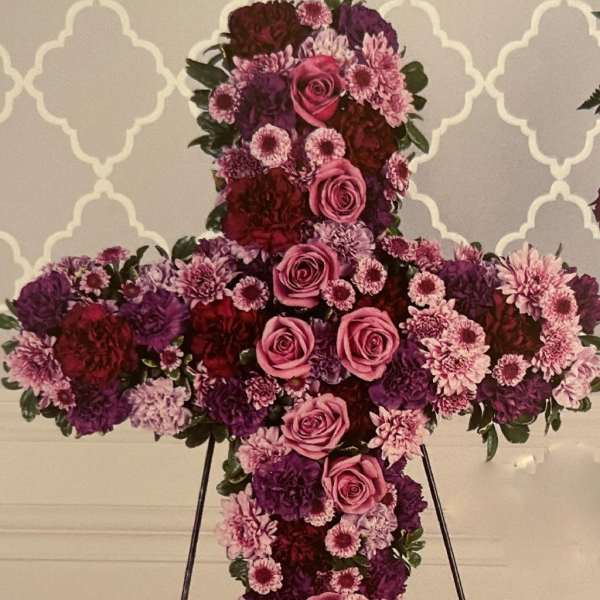 Large floral cross on an easel with pink and purple flowers