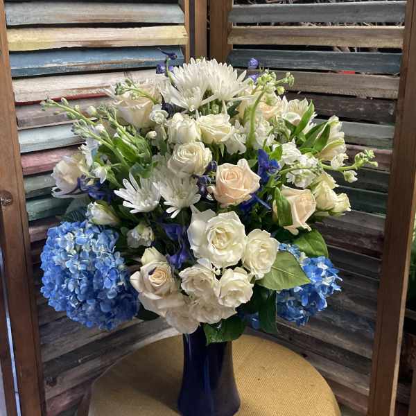 White and blue floral arrangement in a dark vase