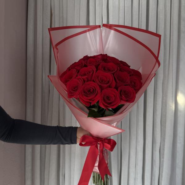 Bouquet of red roses wrapped in pink paper with a red ribbon