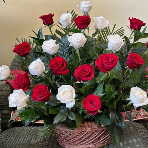 Basket arrangement of red and white roses with palm fronds