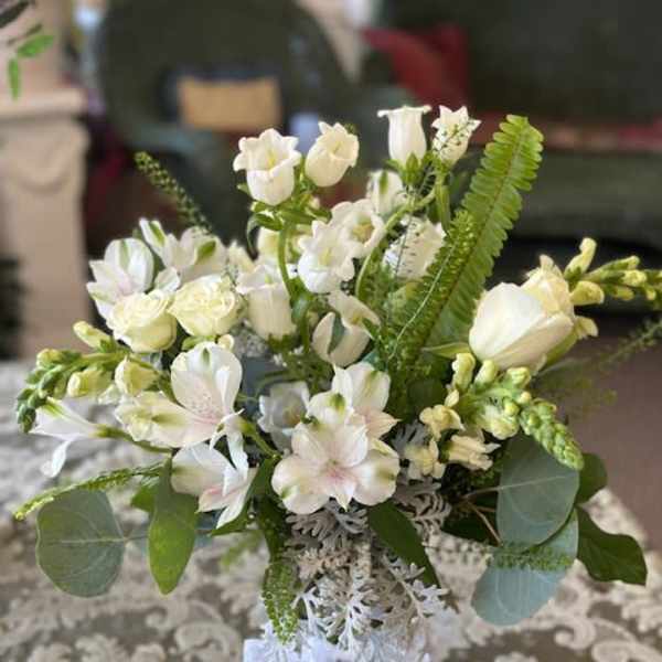 White floral bouquet in a glass vase with a ribbon