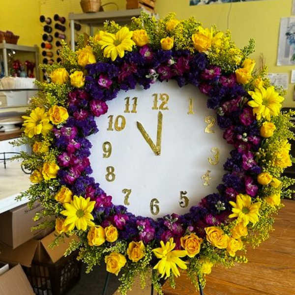 Large floral wreath around a white clock face on an easel