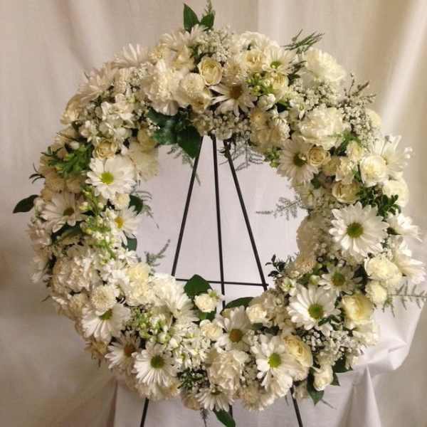 White floral wreath on a black stand
