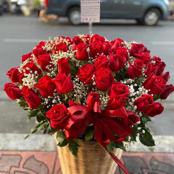 Basket of red roses with baby's breath and a red ribbon bow
