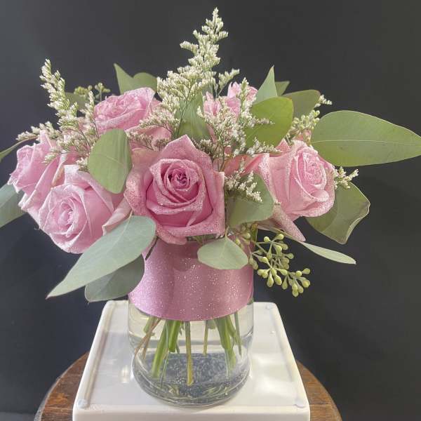 Pink roses in a clear glass vase with eucalyptus and filler flowers
