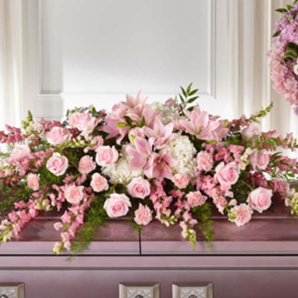Pink floral casket spray with lilies, roses, and carnations