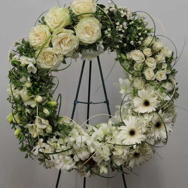 Standing wreath of ivory roses and white daisies on a metal easel