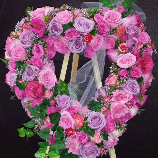 Heart-shaped rose wreath on a wooden easel with trailing ivy