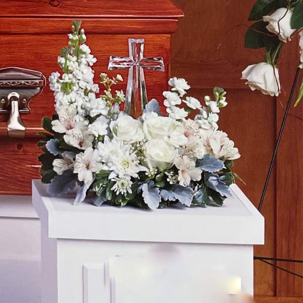 White floral arrangement with roses and a cross centerpiece