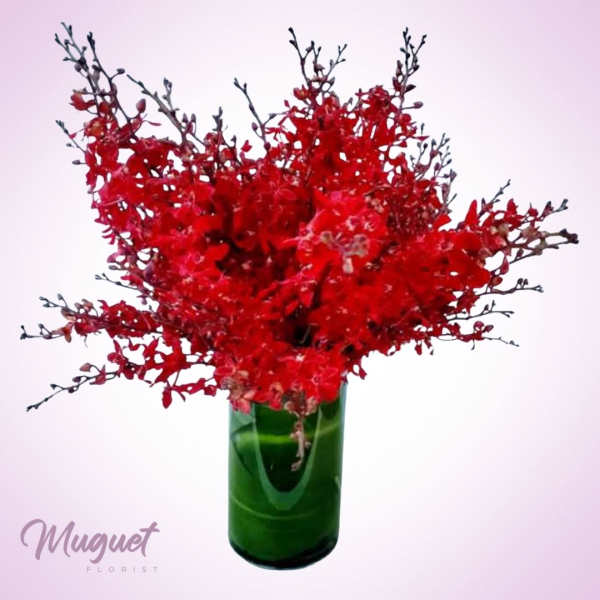 Red floral arrangement in a green glass vase