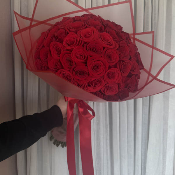 Large bouquet of red roses wrapped in red-edged paper