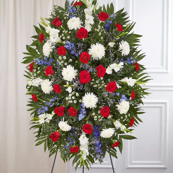 Standing funeral spray with red roses, white chrysanthemums, and blue flowers