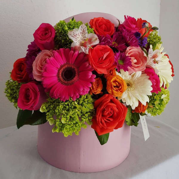 Mixed bouquet of roses and gerbera daisies in a pink hat box