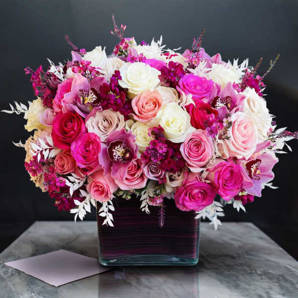 Pink and white rose bouquet in a square glass vase