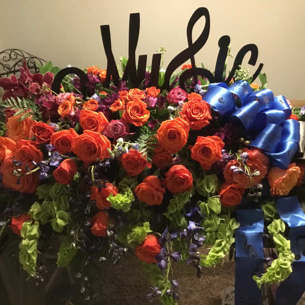 Large floral arrangement with orange roses and blue ribbons