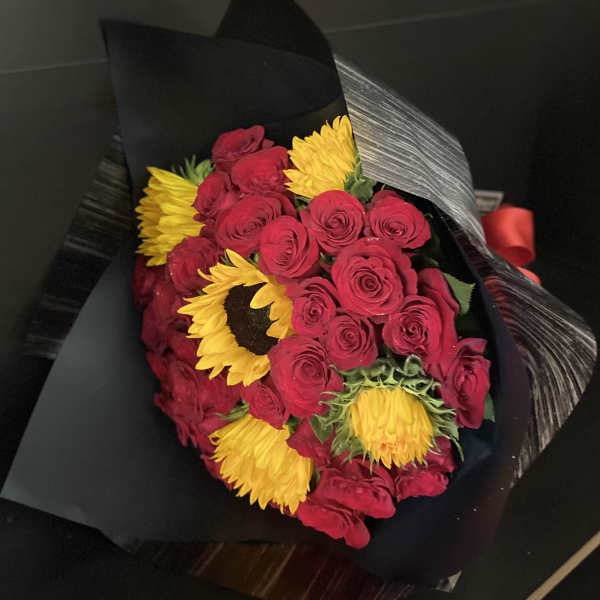 Bouquet of red roses and yellow sunflowers wrapped in black paper