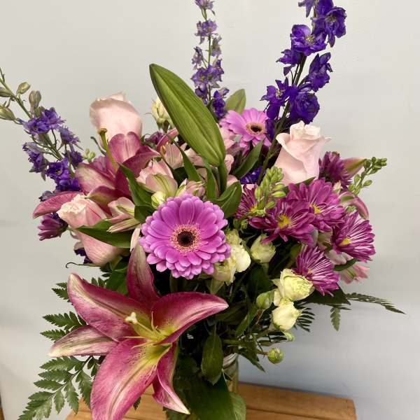Mixed bouquet of pink and purple flowers in a glass vase