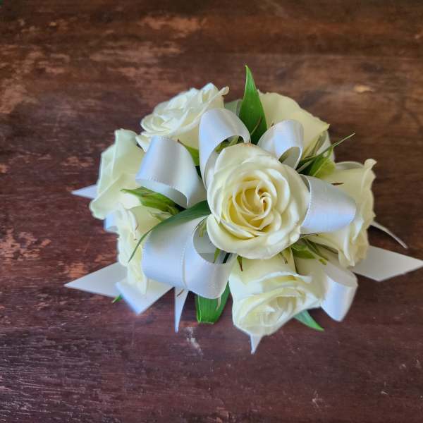 Small bouquet of white roses with white ribbon on a wooden surface