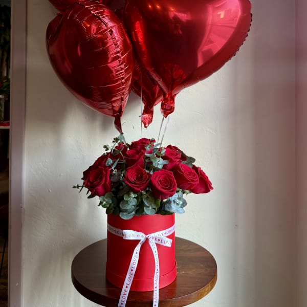 Red roses in a round box with red heart balloons above