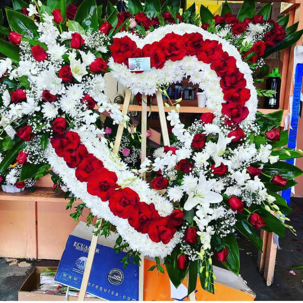 Heart-shaped floral wreath of red roses and white flowers on an easel