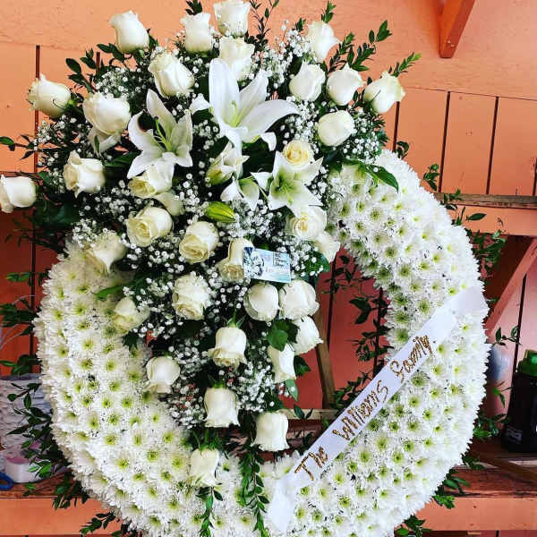 White rose and lily funeral wreath with a ribbon
