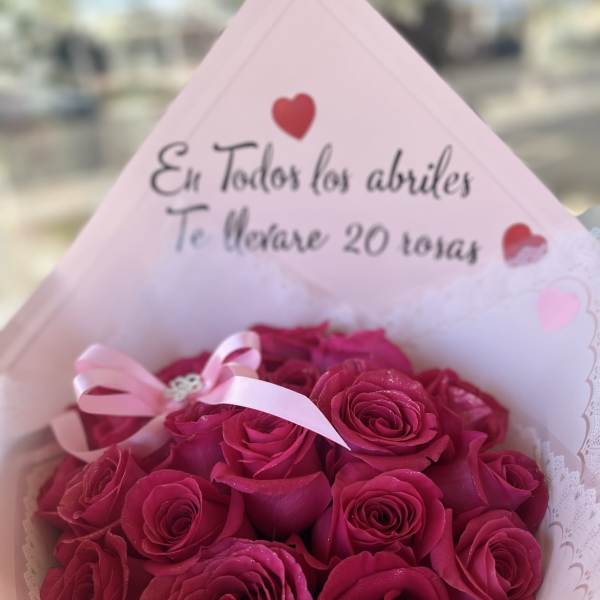 Bouquet of deep pink roses wrapped in pale pink paper with a ribbon
