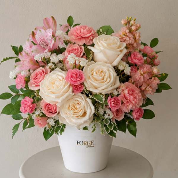 Pink and cream flower arrangement in a white pot