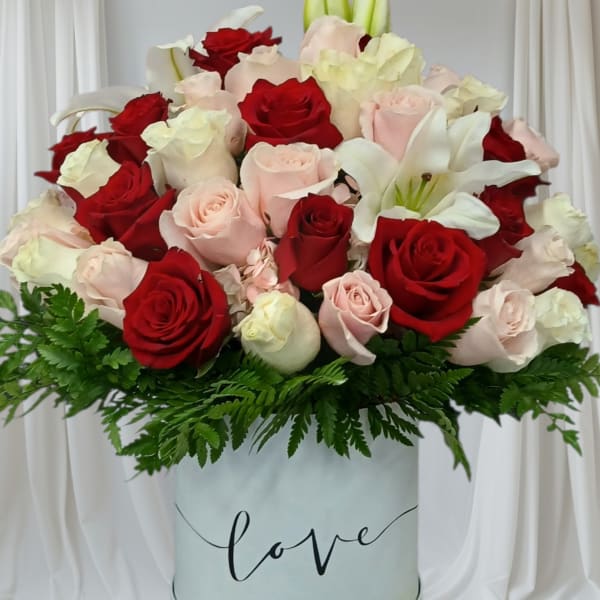 Red and blush roses with white lilies in a round box