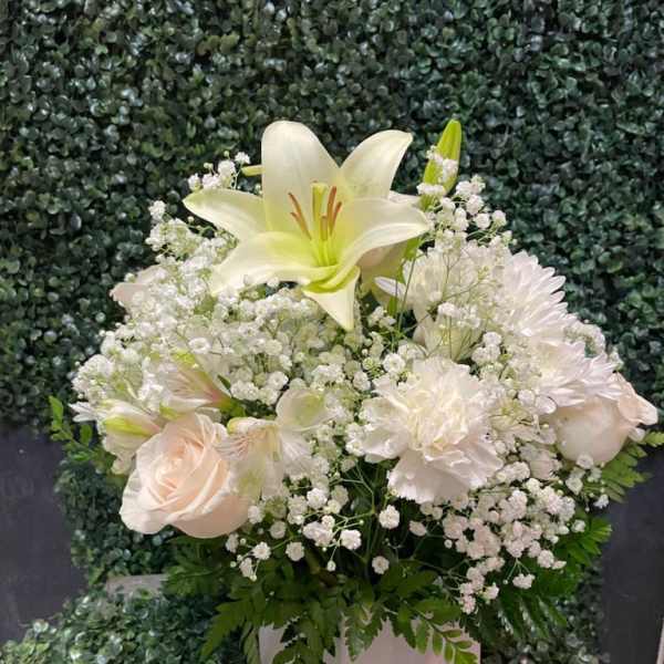 White lily and pale blooms in a white vase