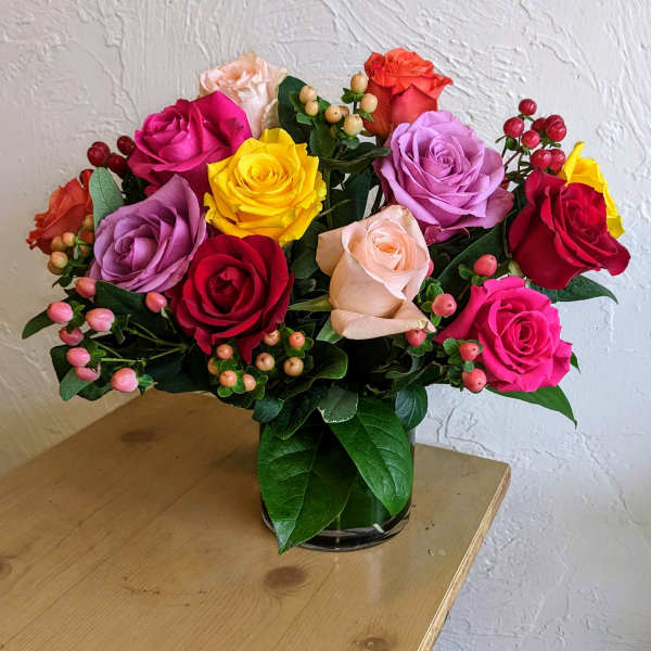 Mixed roses in a glass vase with berry accents