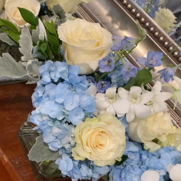 Cream roses and blue hydrangeas arranged in glass containers