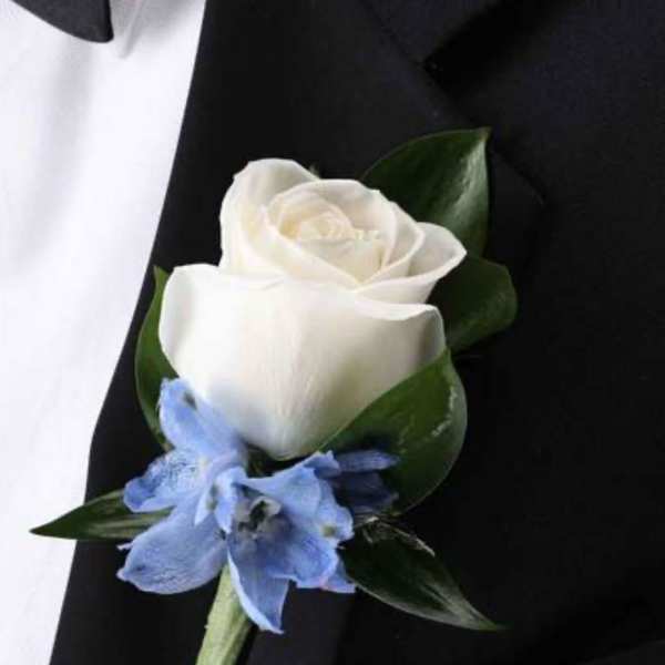 White rose boutonniere with a blue accent flower on a black suit