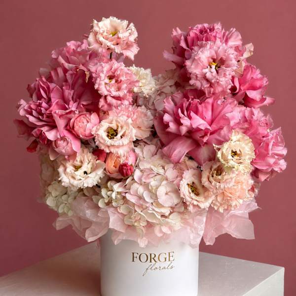 Pink and white floral arrangement in a white hat box
