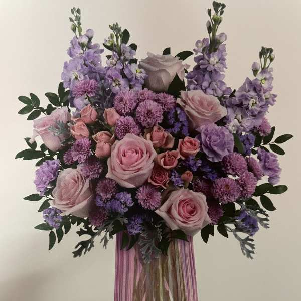 Pink and lavender bouquet in a purple glass vase