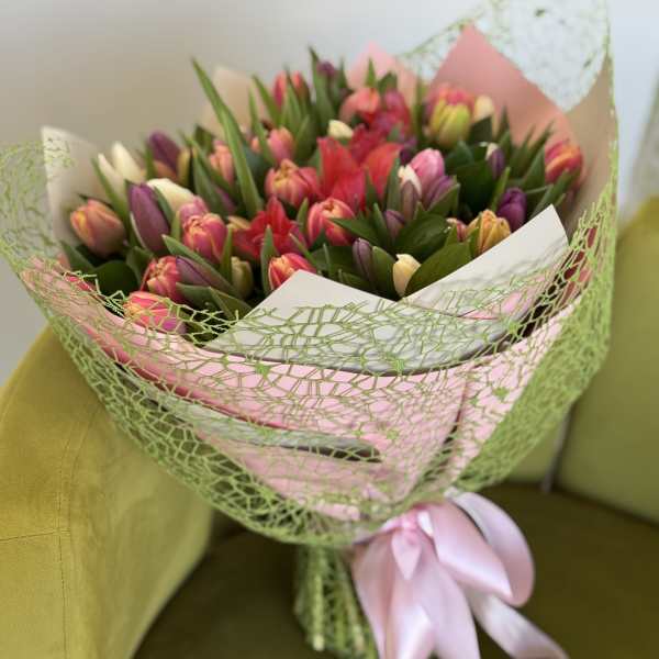 Bouquet of multicolored tulips wrapped in pink and green paper