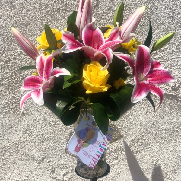 Bouquet of pink lilies and yellow roses in a glass vase