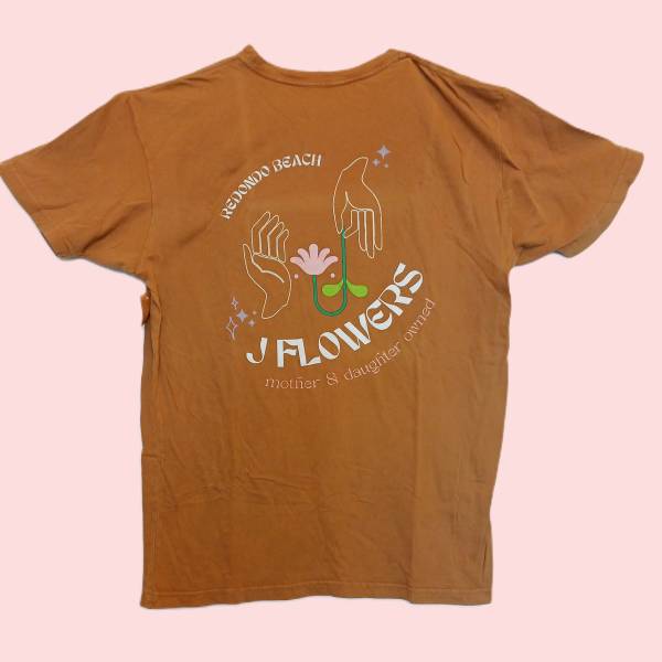 Brown graphic T-shirt with a floral hand illustration and text