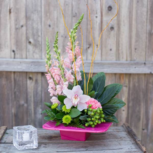 Pink and white floral arrangement in a bright pink vase with tall stems