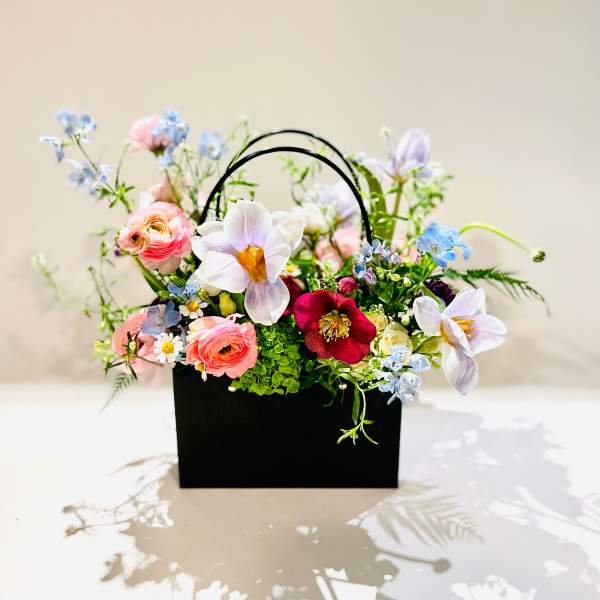 Mixed pastel flowers arranged in a black handled box